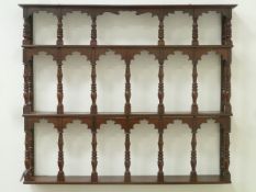 Early 19th century mahogany wall mounted three tier delft rack fitted with turned supports, W111cm,