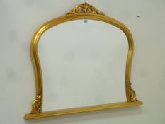 Arch top overmantle mirror in gilt frame with carved pediment,