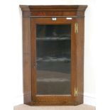Early 19th century oak and mahogany banded corner cabinet enclosed by single glazed door,