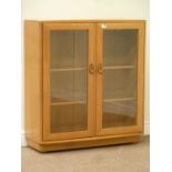 Ercol light elm bookcase enclosed by two glazed doors fitted with two adjustable glass shelves,