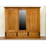 Large pitch pine tripe wardrobe enclosed by three doors including central mirror glazed door,
