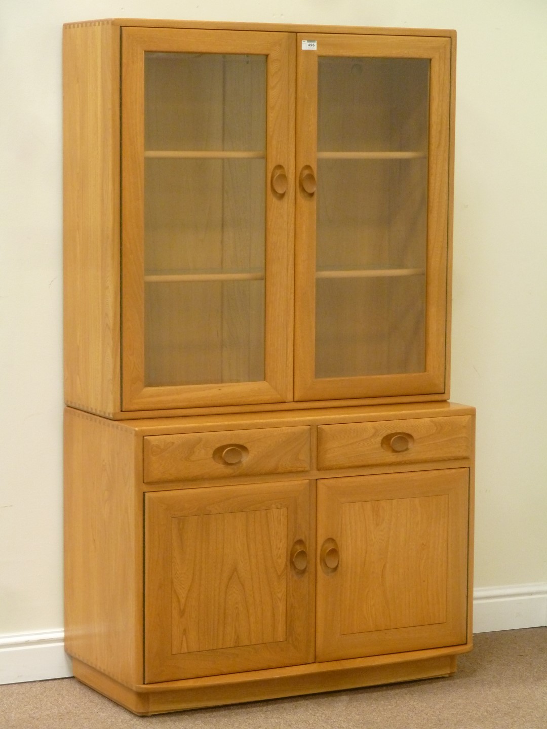 Ercol light elm display cabinet enclosed by two glazed doors fitted with adjustable shelves,