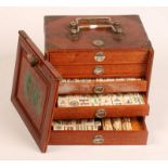A Mahjong set in a hardwood case with a sliding front opening onto five drawers. Condition Report: