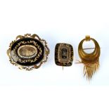 A Victorian matt gold tasseled brooch and two enameled gold mourning brooches.