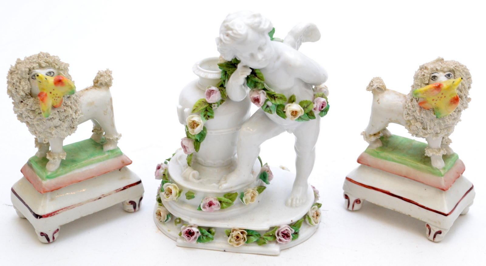A pair of Staffordshire style small poodles, each stands four square with a bird in its mouth,