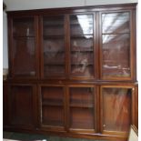 A large mahogany bookcase with two levels of four glazed doors opening onto adjustable shelves.