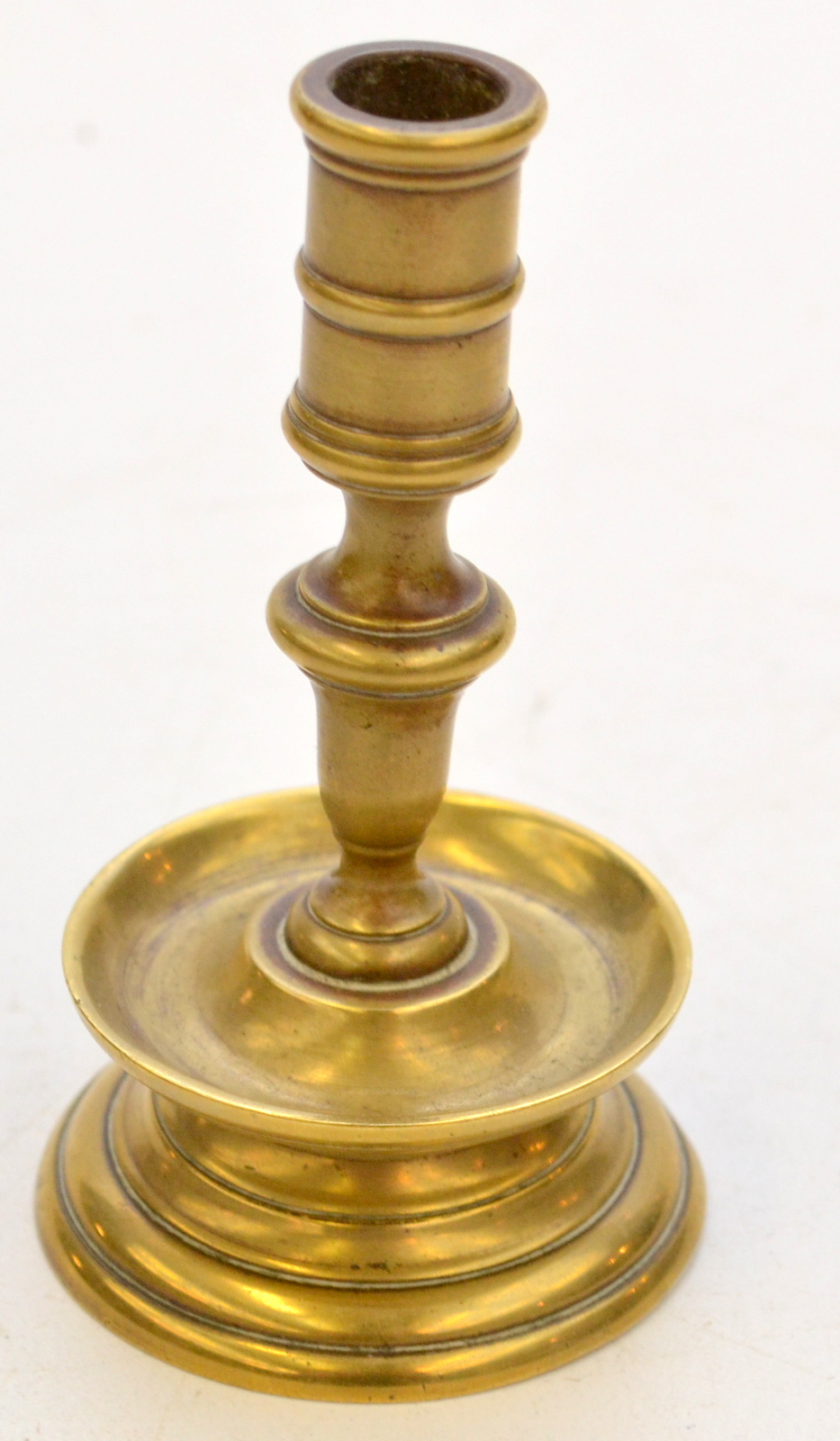 A small 17th century Dutch style brass taper stick, with a drip pan above a bell shape base,