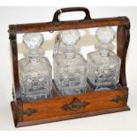 An oak tantalus with three decanters. Condition Report: The metal mounts are slightly corroded.