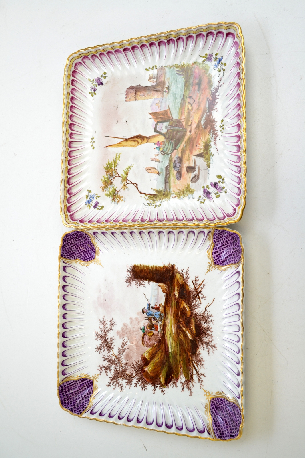 A pair of faience square fluted dishes, one painted with a coastal shipping scene,