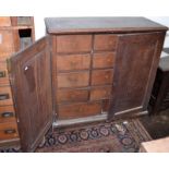 A George III oak cupboard with a pair of panelled doors opening onto three tiers of four drawers,