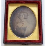 A mid 19th century oval Daguerreotype of a girl, length 5.5cm, in a red leather case, 7.5 x 6cm.