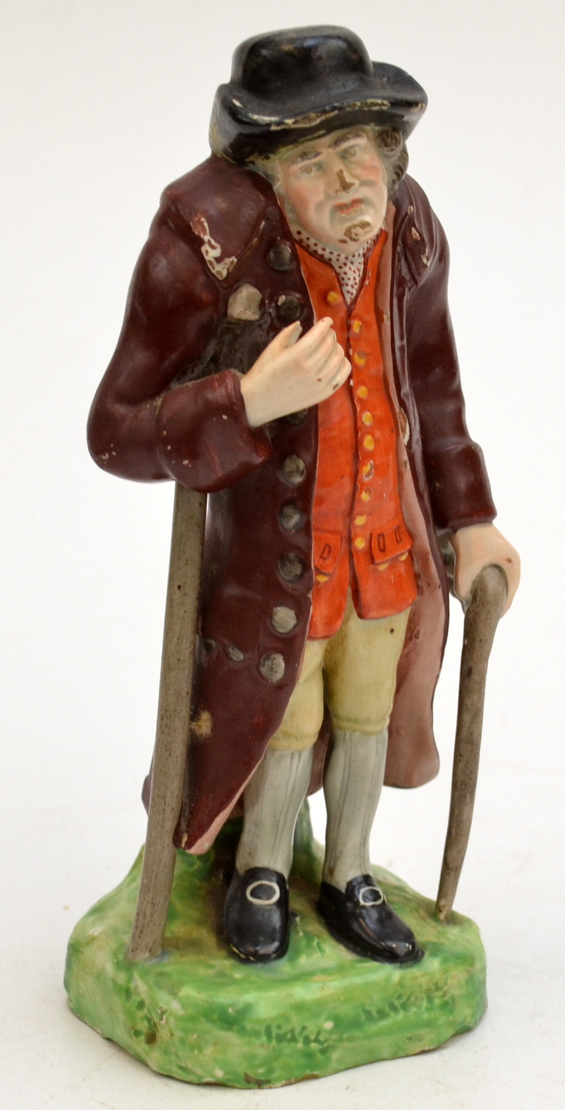 An early 19th century Staffordshire figure of an old gentleman, he walks with a stick and a crutch,