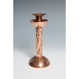 A Newlyn copper candlestick, with a drip tray above pilchards on domed foot. Impressed mark.