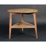 An early 19th century fruitwood cricket table with triangular shelf, the top 76cm diameter.