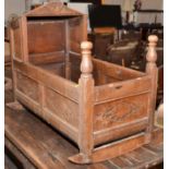 A 17th century joined oak cradle the canopy with linen fold, pitched roof and carved front,