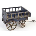 A wooden toy cart with cast iron wheels, width 19cm.