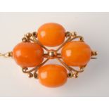 A gold crossform brooch with four amber beads.