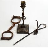 A miners' wrought iron candle holder, a bronze candlestick and a pair of handcuffs.