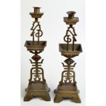 A pair of Chinese brass candlesticks with characters in Zhuanshu script.