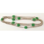 A long silver chain necklace spaced with green jade, oval beads.