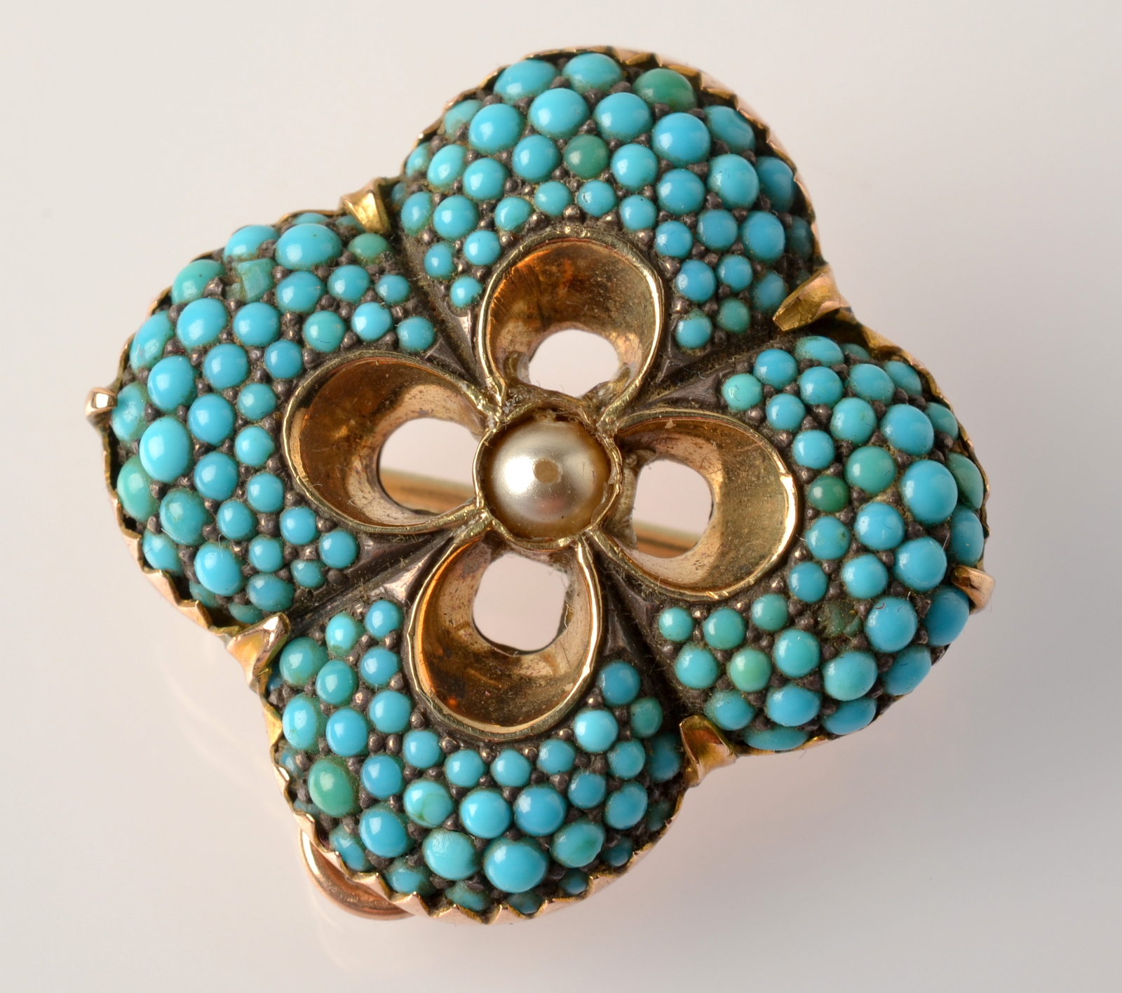 A Victorian quatrefoil gold pendant/brooch pave set with turquoise about a central pearl.