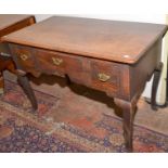 A mid 18th century oak lowboy with three drawers above a shaped apron on angular, cabriole legs,