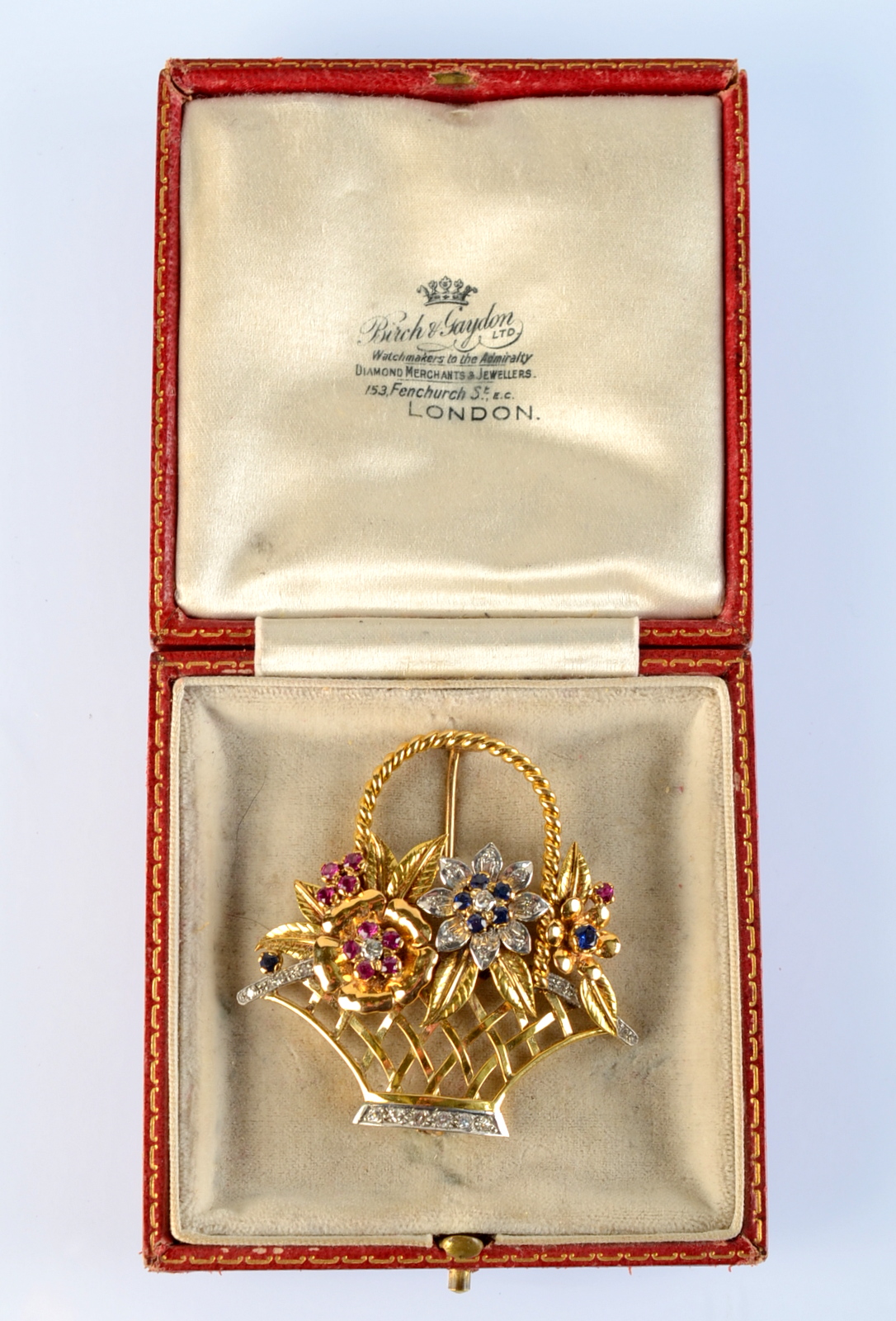 A gold basket brooch, set with rubies, diamonds and sapphires.
