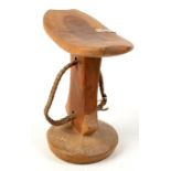 An African light wood head rest with plaited leather attachment and aluminum repair, height 16.5cm.