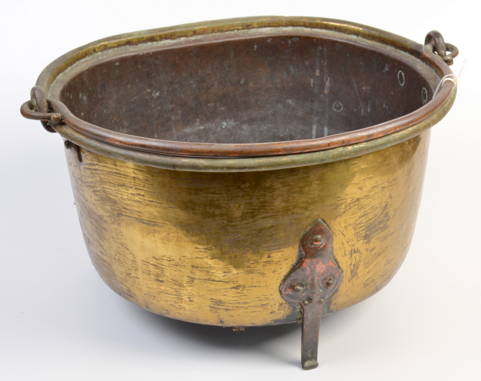 A brass preserve pan with copper legs and swing copper handle.