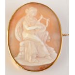 A gold cameo brooch carved with a lady playing a lyre.