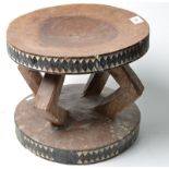 An African stool with shallow geometric carving coloured black and white on four angular supports.