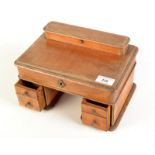 A late Victorian ink stand in the form of a twin pedestal desk with a stamp and pen compartment,