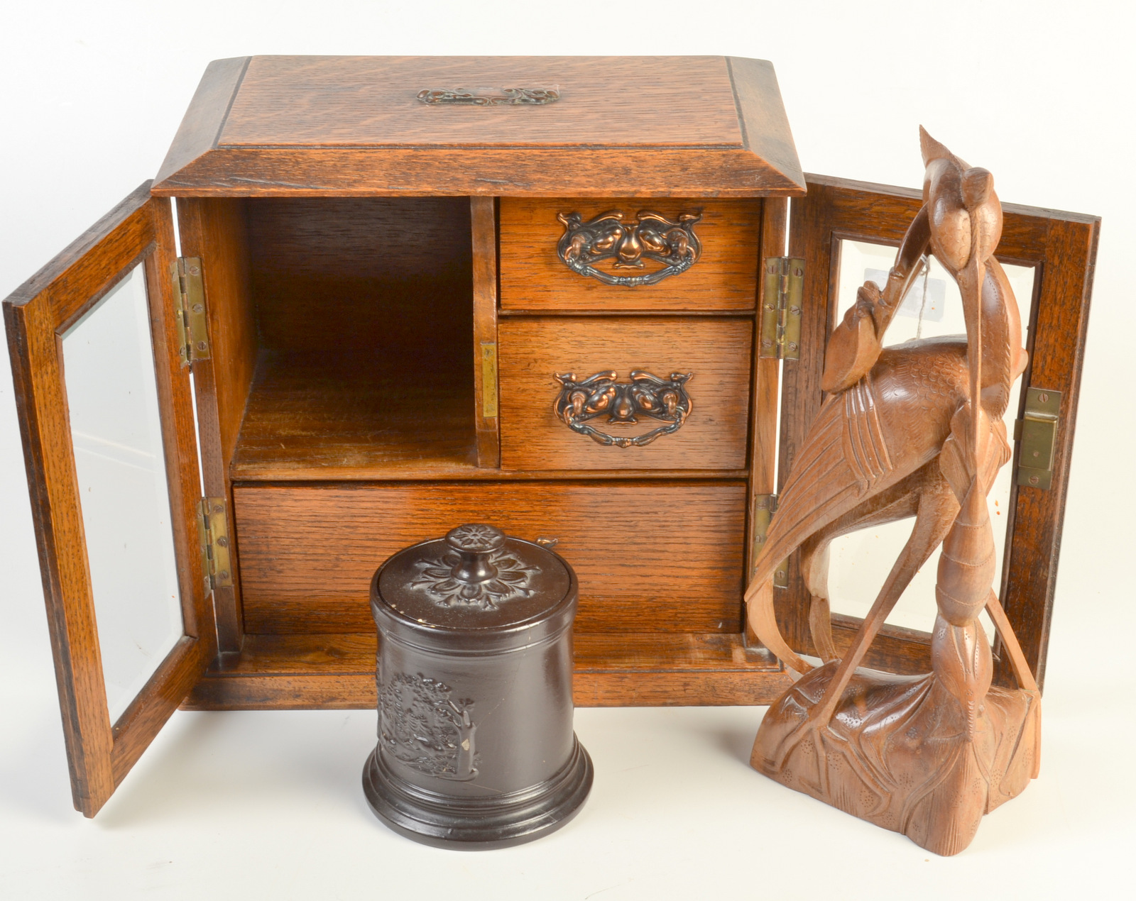 A smokers' oak cabinet, an Austrian ceramic tobacco jar and an Eastern carved wood bird.