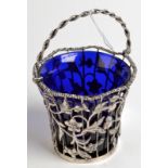 An Edwardian silver sugar basket with twisted swing handle and blue glass liner,