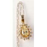 A fine diamond pendant with a central yellow, pear shaped diamond surrounded by brilliants,