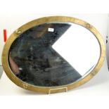 An Art Nouveau oval mirror with bevelled glass in a brass frame.