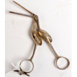 A pair of silver coloured metal novelty ribbon pulling scissors in the shape of a stork oening to