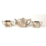 A Chinese early 20th century silver three piece tea service with applied flowering prunus design,