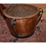 A laundry copper mounted as a log bin with wrought iron stand.