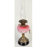 An Edwardian oil lamp with white floral painted moulded pink glass font.