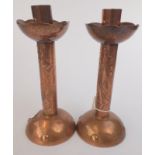 A pair of Newlyn copper candlesticks, each cylindrical stem with a group of vertical fish on mound