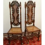 A pair of high back carved walnut chairs in William and Mary style with carved decoration.