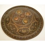 An Indian brass Dahl shield patterned with a black foliate design and with four raised bosses.