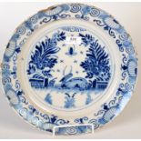 An 18th century English delft blue and white dish with a foliate border, the centre painted with a