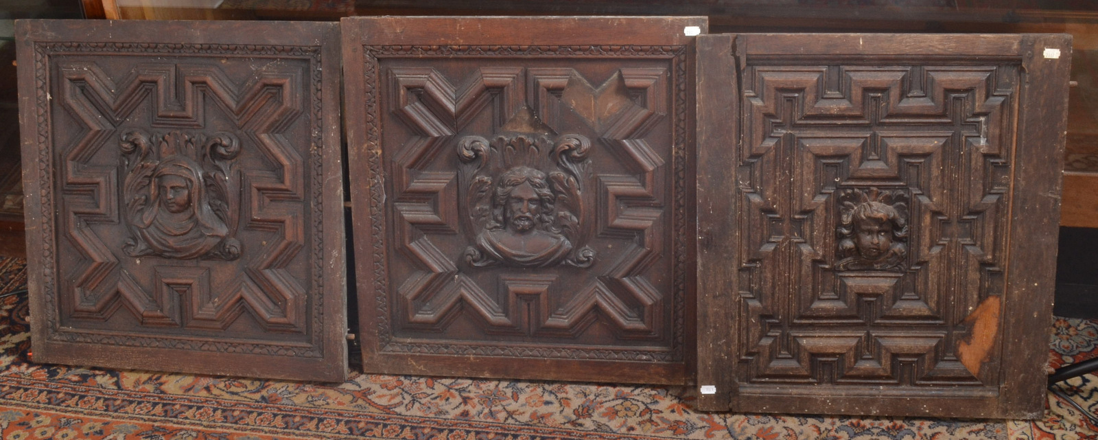 Three oak panels, the centre of each with a carved head possibly 16th century.