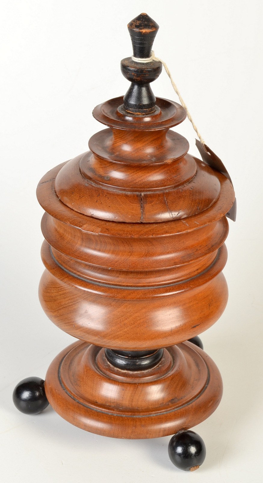 A 19th century continental turned walnut lidded tobacco jar, standing on three ebonised ball feet,