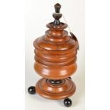 A 19th century continental turned walnut lidded tobacco jar, standing on three ebonised ball feet,