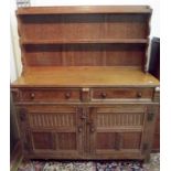 An Arts and Crafts light oak dresser with open low rack, retailed by Maple, width 123.