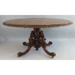 A Victorian rosewood breakfast table, having oval tilt top with carved edge on central turned column