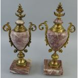 A pair of continental urns, the pink veined marble bodies and bases with gilt metal mounts,